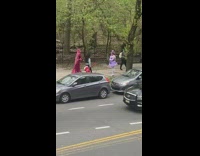 Three Models in Colorful Costumes Walk Down Sidewalk 