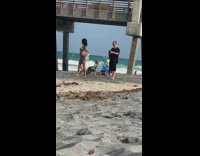 Woman in Green Bikini Poses with White Cardigan on Sand 
