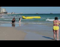 Woman in white bikini kneels on shore 