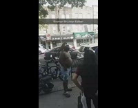 Shirtless man white durag distressed jean shorts has parrot on his shoulder on sidewalk