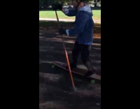 Man on longboard using stick to skate through park