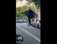Man on stilts flap cape while walking