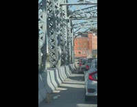 Old man climbing in between rails on bridge