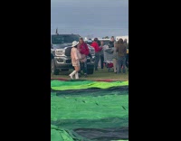 Woman in a pink cowboy outfit spins near the deflated hot air balloon