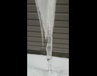 Large icicle hangs under white pipe 