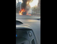 Suv car on fire on side of road and fire gets onto grass