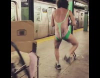 Guy in latex green unitard streaming iphone stand subway