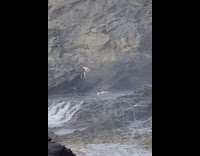 Girl lays facedown waterfall black rocks 