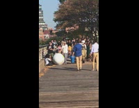 Guy rolls big inflatable earth globe down dock with crowd following behind
