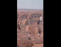 Parents on rock cliff kids throw rocks
