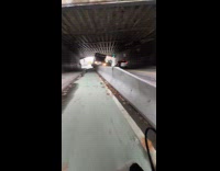 Truck stuck on concrete barrier under bridge