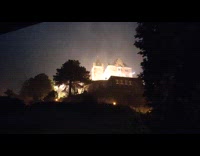 Thunderstorm with continuous lightning behind lit house