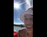 Two girls in raft look at wild white horse in water