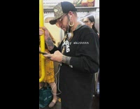 Man with stretched ear plugs wears hanging clock on his ears