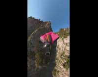 Lady wearing wing jacket flies over trees 