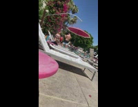 Lady in white bikini stands next to chair at pool for photos 