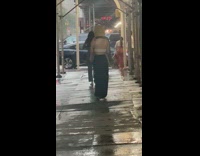 Lady walks with paper bag on head in the rain 