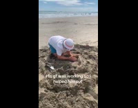Man with filmer makes sandcastle for girlfriend