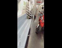 Guy rides subway train with red motorcycle 