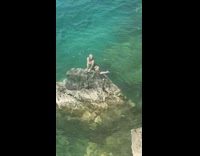 Woman in black bikini on the pointy beach rock