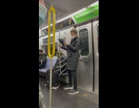 Guy sits under red blanket on subway 