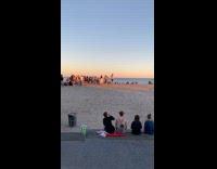 Crowded beach black shorts person handstand sunset