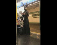 Man in black lace fringe goth clothing black bunny ears mask on subway train