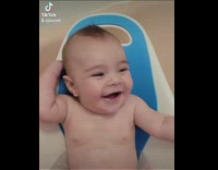 Baby boy laughs inside bath chair