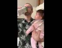 Baby watching dad drink milk from carton 