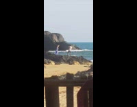 Woman blue dress dances at beach rocks