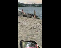 Woman pink dress sit down beach rocks photo shoot
