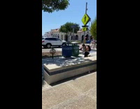 Black shirt girl sidewalk two trash cans 