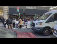 Pile of trash on the street by sidewalk with people browsing