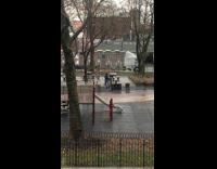 Two men fight at park across the street next to benches
