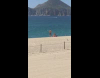 Guy photographs lady sitting on beach sand