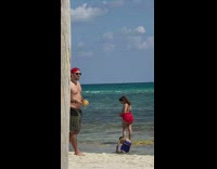 Woman in bikini poses at the beach with a drink