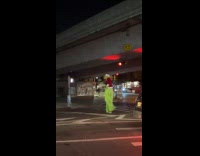The Grinch on stilts cross the road