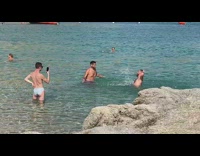 Three shirtless men splash beach water photoshoot