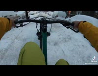 Guy riding bicycle does wheelie snow street