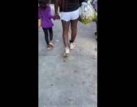 Woman walks on sidewalk with ankle monitor