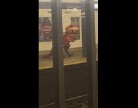 Person with human sized dinosaur balloon in subway platform