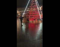 Girl poses by red light christmas tree