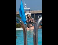 Woman in bikini adjusts bra at pool