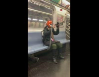Woman wears orange fox helmet on subway train