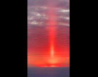 Red sunset sun pillar on sky horizon