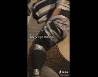 Woman sitting at edge of bed next to guy tied up with duct tape