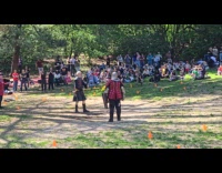 Two men medieval armor fight park crowd