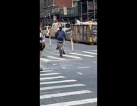 Guy carries large object while riding bicycle 
