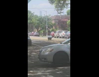 Guy biking on the street while pulling a small box 

