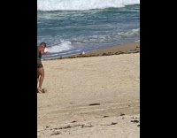 Guy practices playing soccer on beach sand 